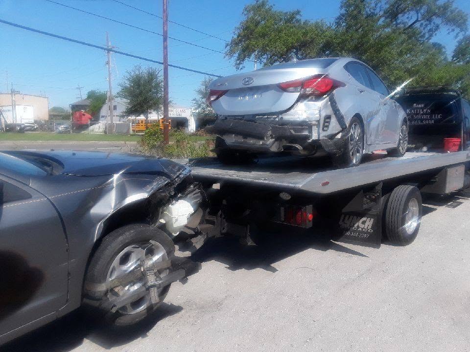 Baby Kaitlyn Towing flatbed truck with a wrecked car on bed and a second wrecked vehicle being towed